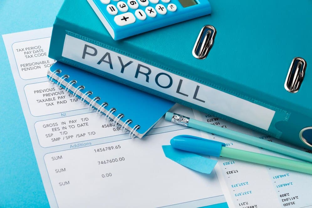 A slip showing gross income, tax and a book named payroll - How to Calculate Your PAYE Tax in Nigeria- BizEdge post