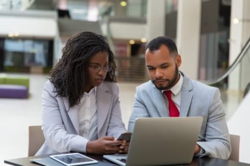 a man looking at a woman surprised with the data on the paper he is holding - performance review biases - BizEdge blog