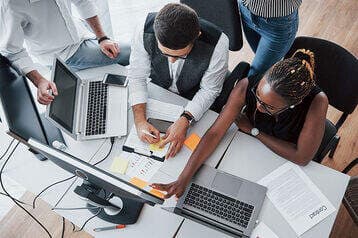 group of people working on the same desk - build future ready teams - BizEdge blog