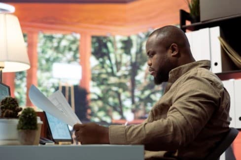 A man at his desk looking at a document - Who Is Responsible for Verifying an Employee Reference Before Hiring