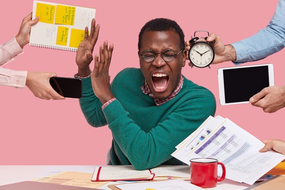 The picture of a man overwhelmed with numerous tasks - BizEdge blog - The Top Scheduling Mistakes Wasting Your Time