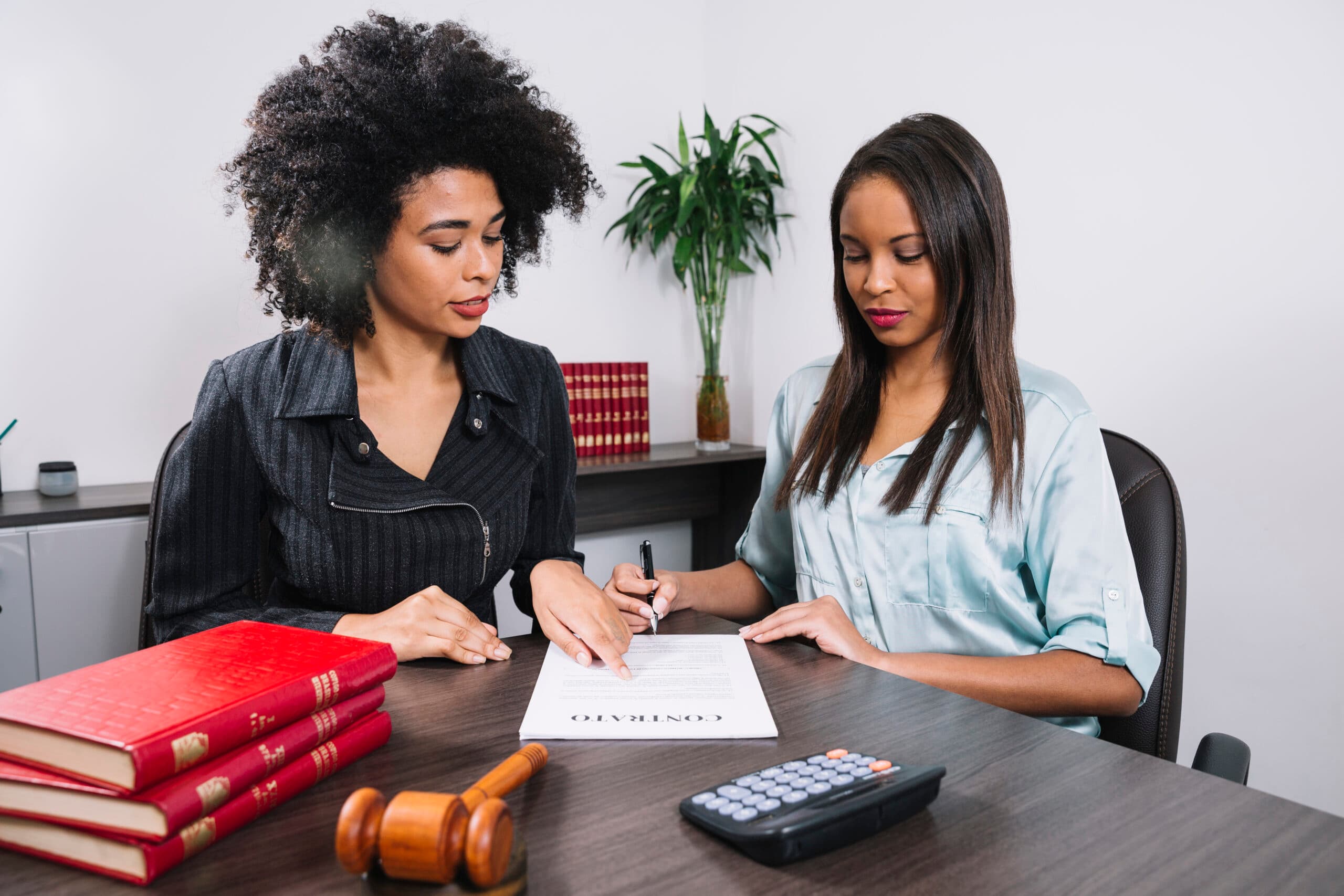 A woman pointing at a document to another lady - Payroll Compliance - BizEdge blog