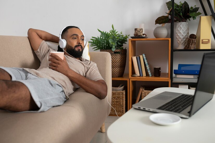 a man spending his time off at home watching a movie and holding a cup of coffee.