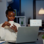A picture of a woman drinking a coffee during a virtual meeting with team members - How to Boost Productivity with Employee Self-Service Portal - BizEdge post