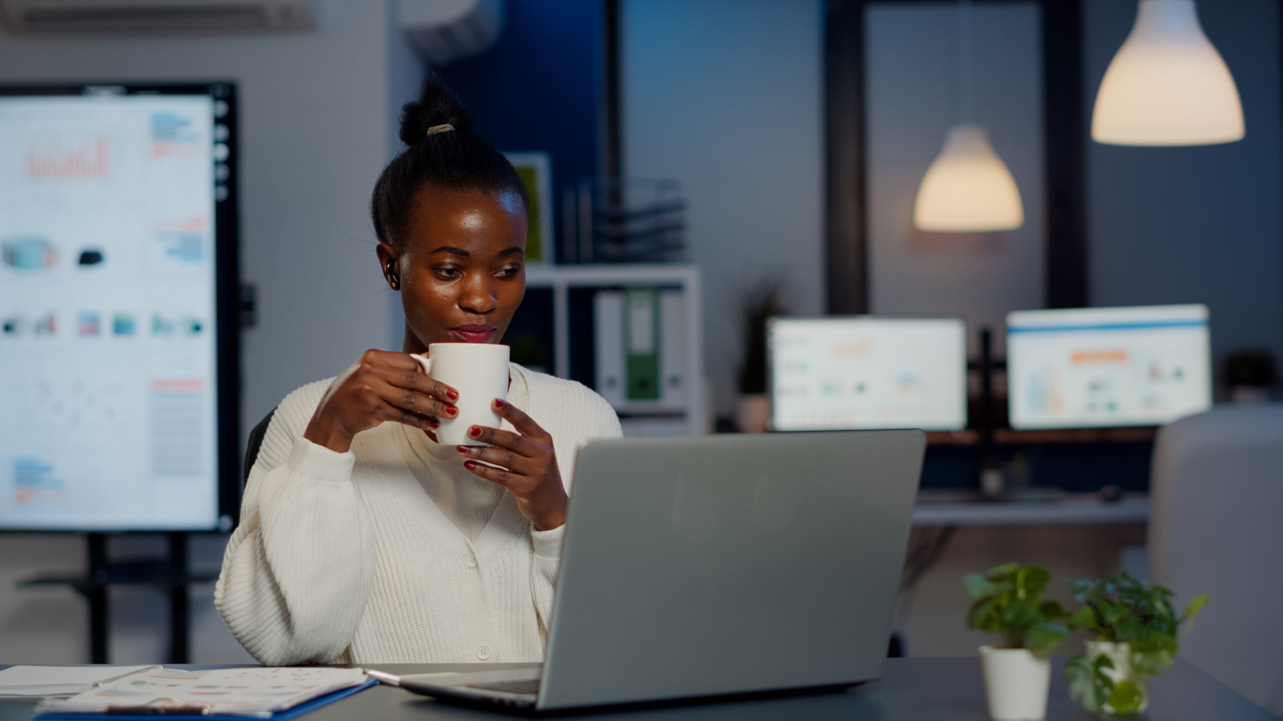 A picture of a woman drinking a coffee during a virtual meeting with team members - How to Boost Productivity with Employee Self-Service Portal - BizEdge post