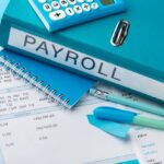 A slip showing gross income, tax and a book named payroll - How to Calculate Your PAYE Tax in Nigeria- BizEdge post