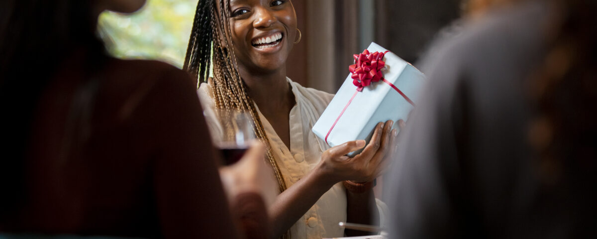 close up smiley woman holding gift- 10 Employee Appreciation Ideas Every HR Leader Should Know - BizEdge blog