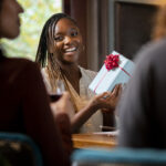 close up smiley woman holding gift- 10 Employee Appreciation Ideas Every HR Leader Should Know - BizEdge blog