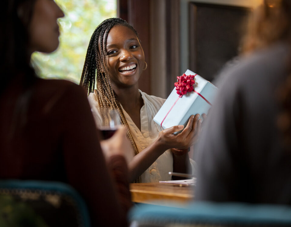 close up smiley woman holding gift- 10 Employee Appreciation Ideas Every HR Leader Should Know - BizEdge blog
