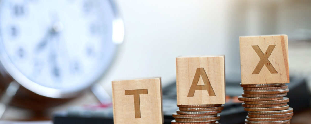 TAX blocks on coin stacks with a clock in the background - 16 New Changes in Nigeria’s 2025 Tax Reform Explained - BizEdge blg