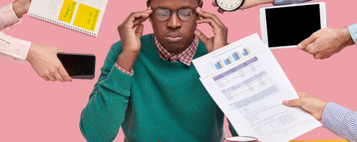 A man surrounded with gadgets and papers - How Busy Teams Can Master Task Prioritization in Simple Steps - BizEdge blog