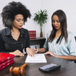 A woman pointing at a document to another lady - Payroll Compliance - BizEdge blog