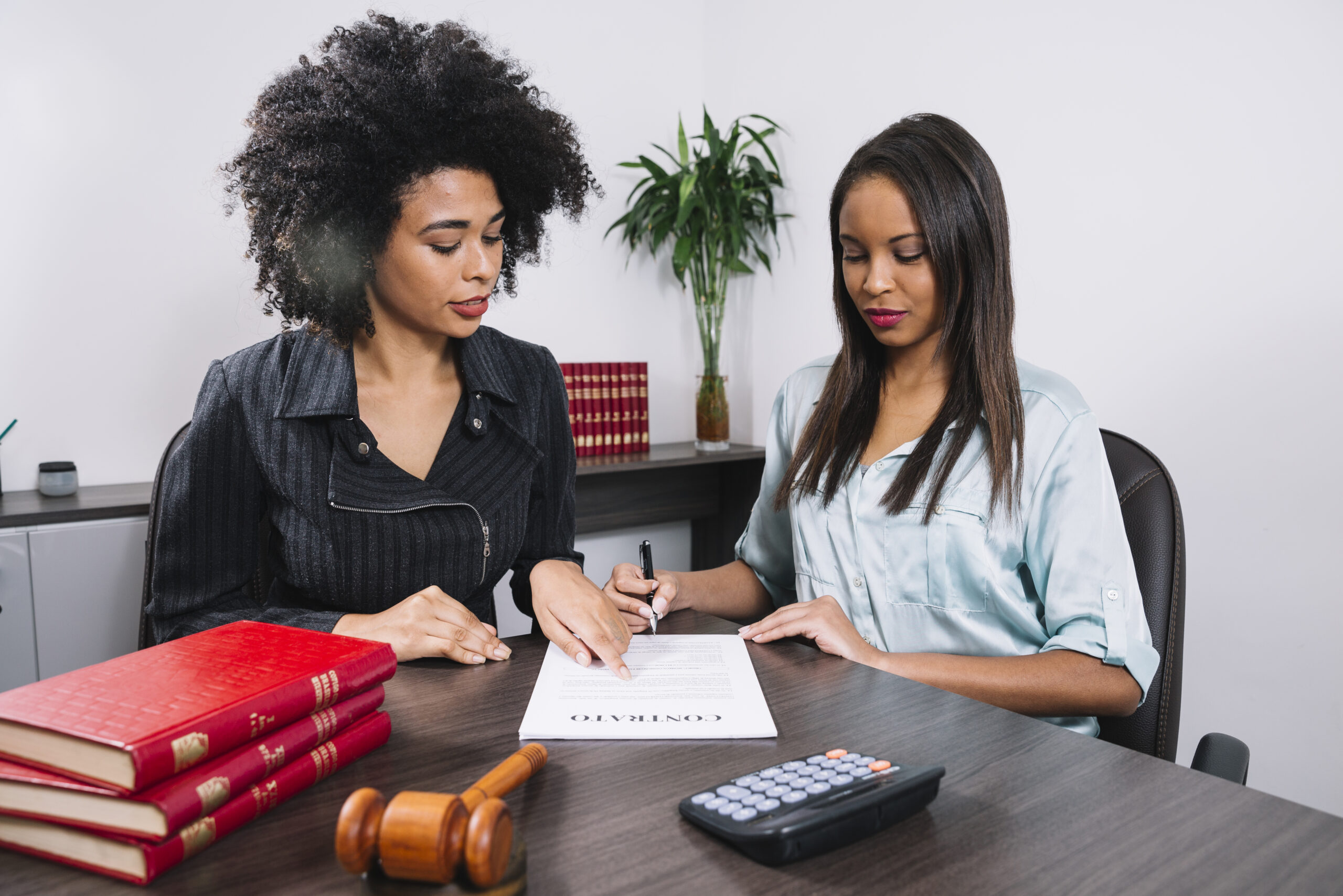 A woman pointing at a document to another lady - Payroll Compliance - BizEdge blog