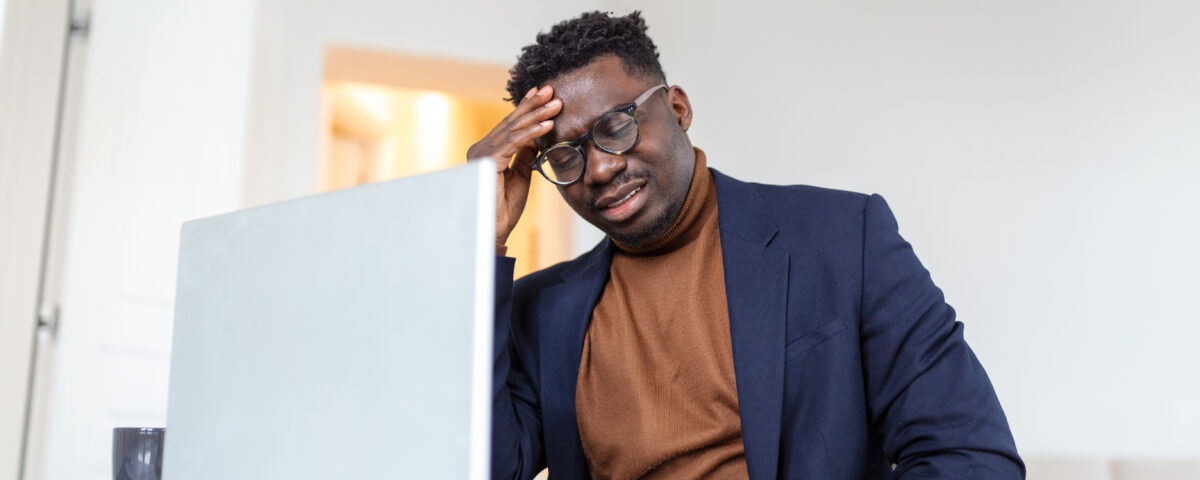 A picture of a stressed man in front of his laptop - How to Manage Employee Downtime Without Losing Productivity - BizEdge blog
