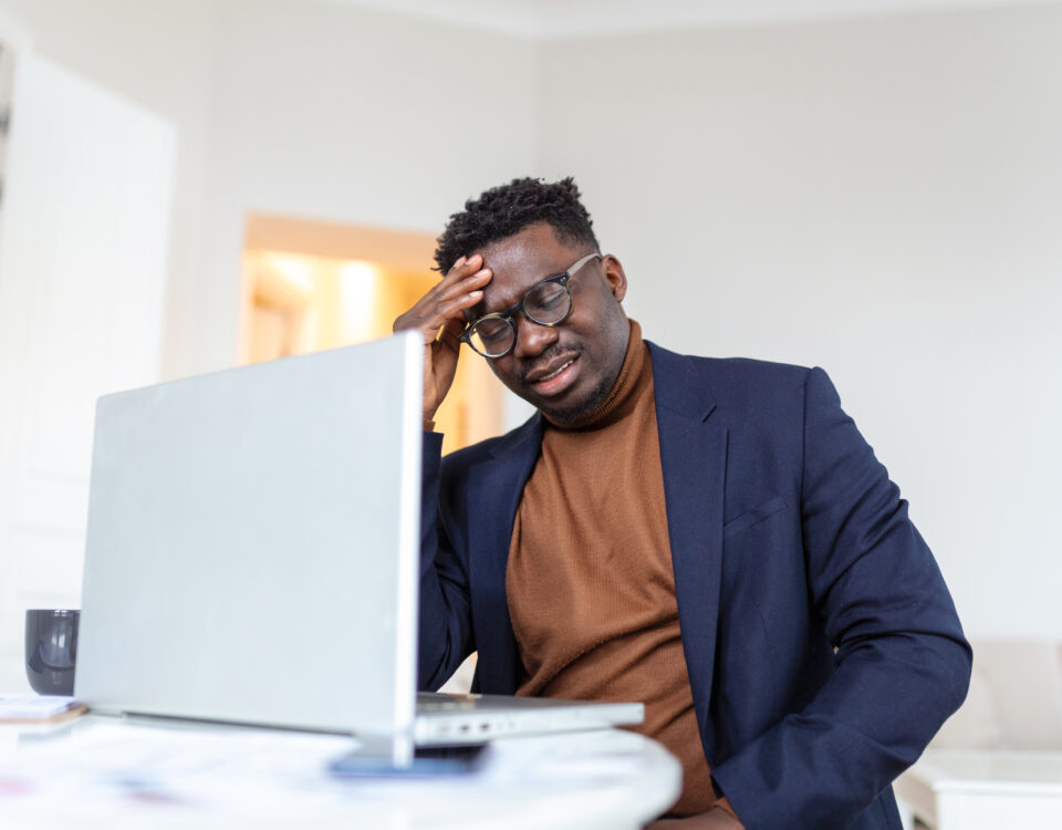 A picture of a stressed man in front of his laptop - How to Manage Employee Downtime Without Losing Productivity - BizEdge blog