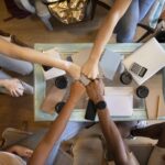 A picture of a group of people fist bumping - 6 Proven Ways to Build a Thriving Workplace Culture - BizEdge blog