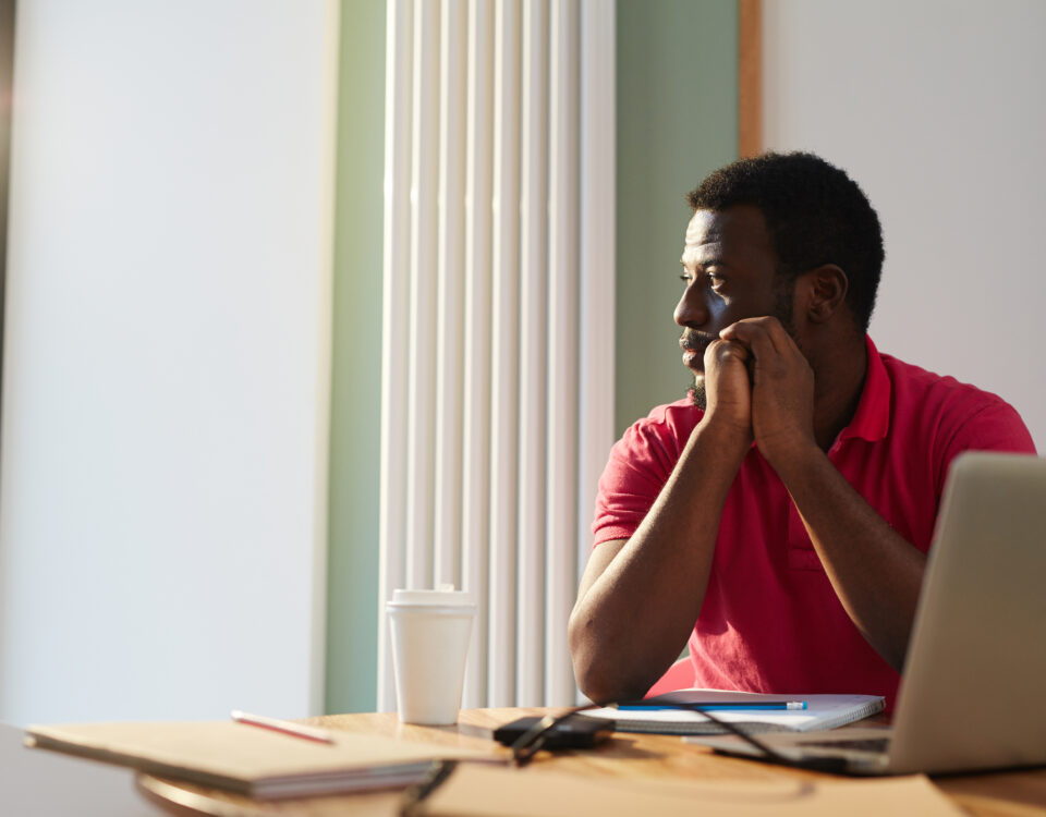 An employee looking through window on sunny day while sitting by desk in office - Employer branding - BizEdge blog