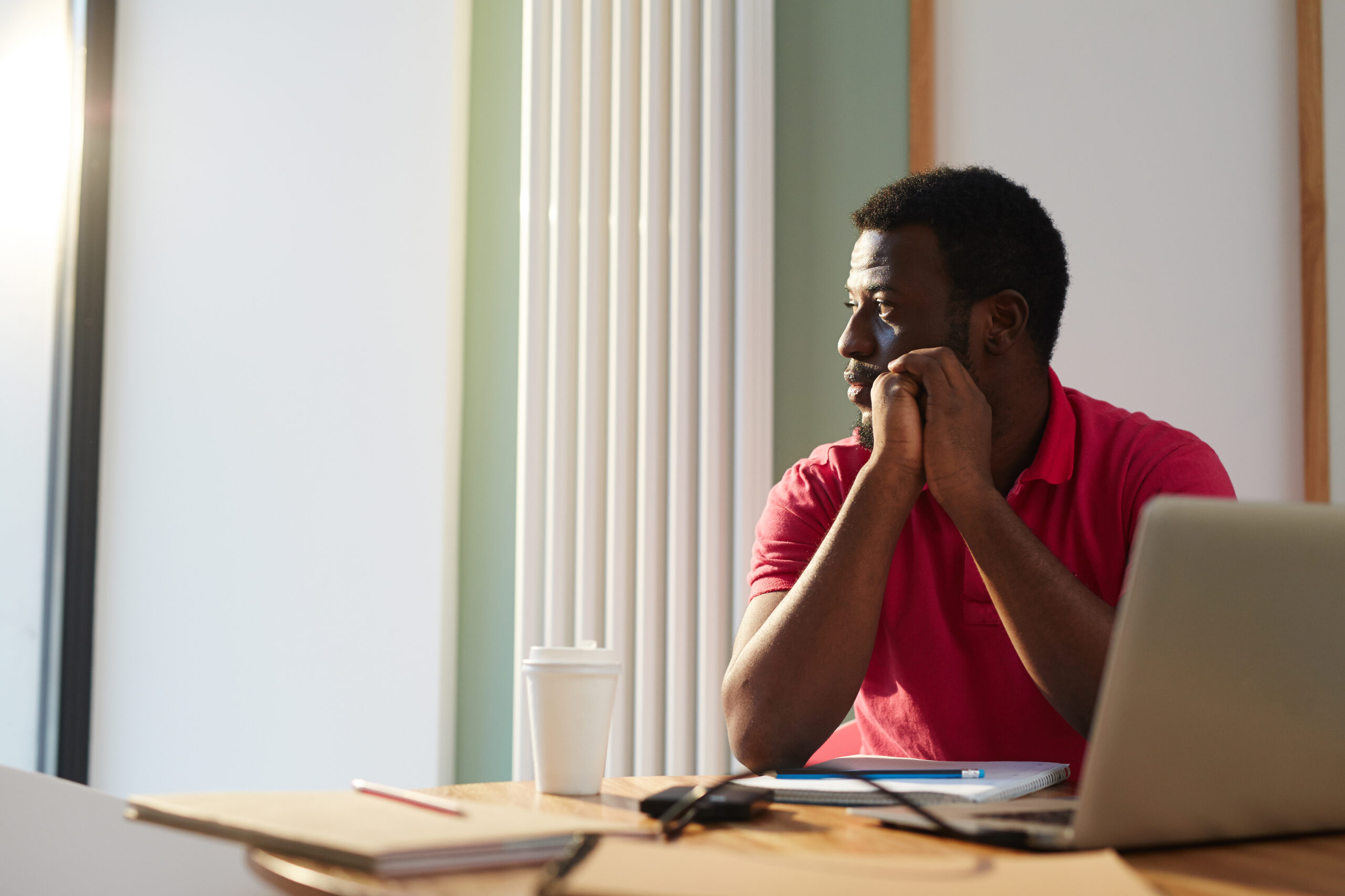 An employee looking through window on sunny day while sitting by desk in office - Employer branding - BizEdge blog