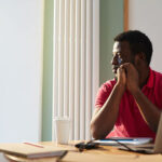 An employee looking through window on sunny day while sitting by desk in office - Employer branding - BizEdge blog