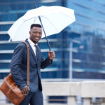 a man with umbrella going to work - rainy season in nigeria- BizEdge blog