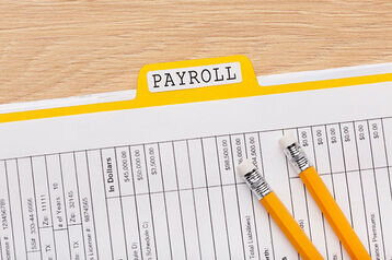 a picture of a payslip with a pen - payroll reconciliation - BizEdge blog