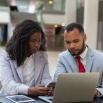 a man looking at a woman surprised with the data on the paper he is holding - performance review biases - BizEdge blog