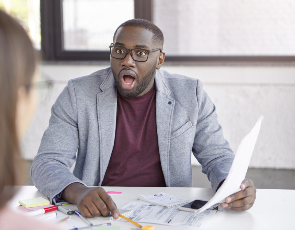 a man looking at a woman surprised with the data on the paper he is holding - performance review biases - BizEdge blog