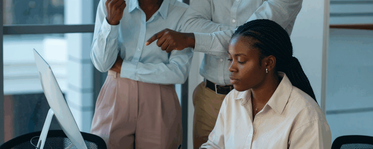 three people gathered and staring at a screen on a lady's desk - agile hr- BizEdge blog