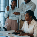 three people gathered and staring at a screen on a lady's desk - agile hr- BizEdge blog