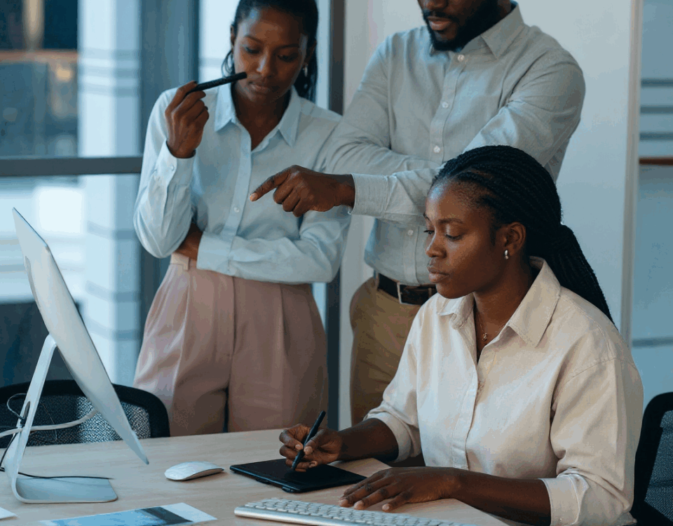 three people gathered and staring at a screen on a lady's desk - agile hr- BizEdge blog