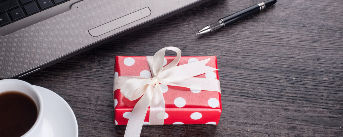 Laptop computer with cup of tea and gift box - Employee Compensation - BizEdge blog