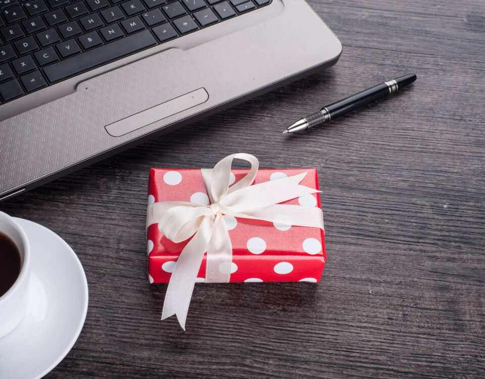 Laptop computer with cup of tea and gift box - Employee Compensation - BizEdge blog