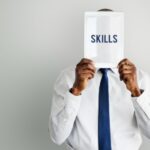 a man holding a pamphlet saying skills written on it - skills gap - BizEdge blog
