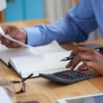 a man calulating with a calculator - Payroll Automation - BizEdge blog