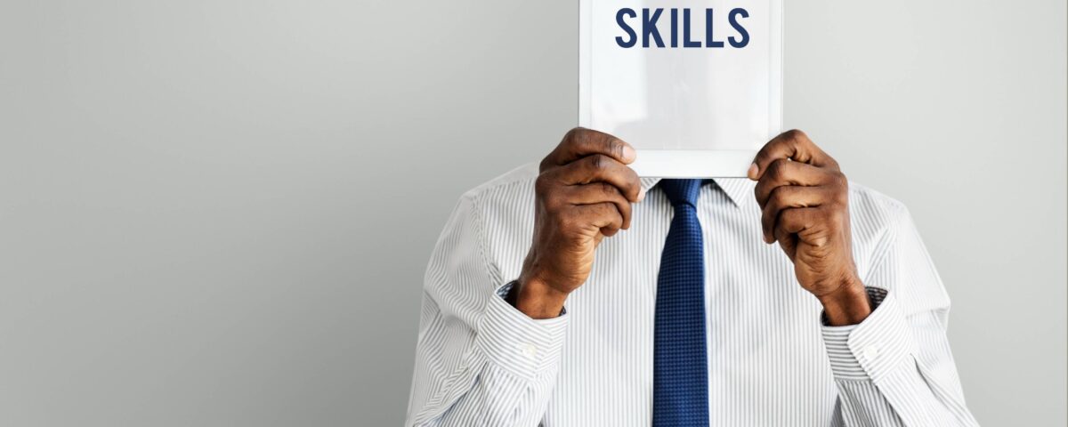 a man holding a paper with the word skills written on it - skills gap - BizEdge blog