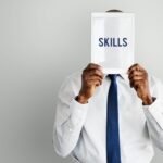 a man holding a paper with the word skills written on it - skills gap - BizEdge blog