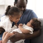 a man holding his daughter in his arms - parental leave - BizEdge blog