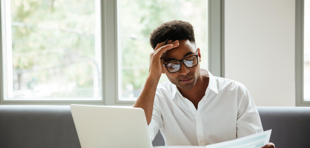 a man looking at a file at his desk - Payroll Decisions - BizEdge blog