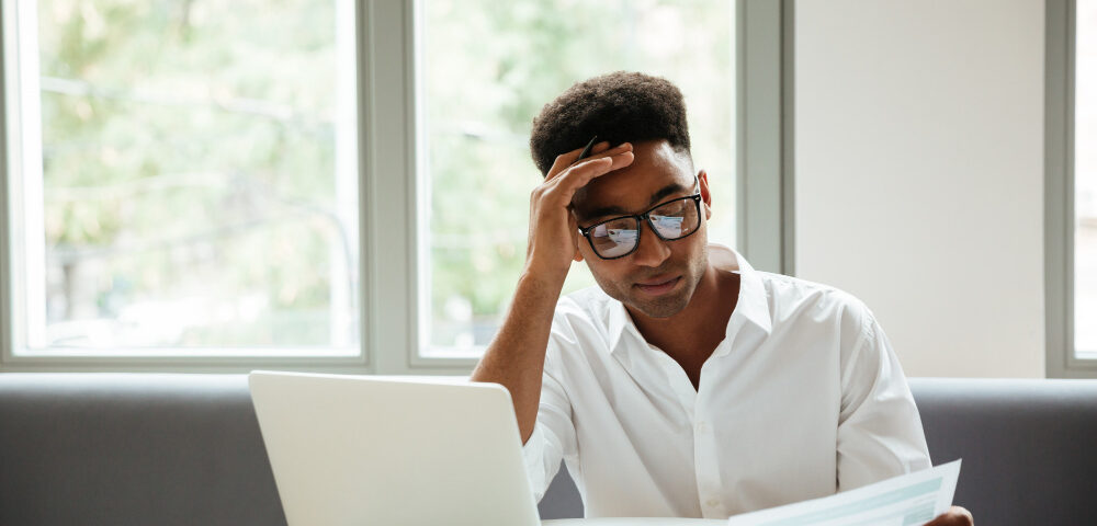 a man looking at a file at his desk - Payroll Decisions - BizEdge blog