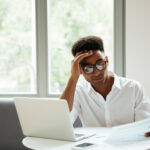 a man looking at a file at his desk - Payroll Decisions - BizEdge blog