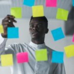 A man placing different sticky note on a wall - task management software - BizEdge blog