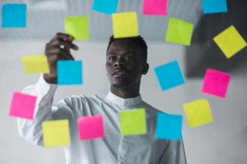 A man placing different sticky note on a wall - task management software - BizEdge blog