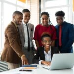 Team members looking at a colleagues laptop - Workforce management strategies -BizEdge blog