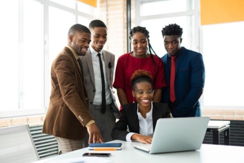 Team members looking at a colleagues laptop - Workforce management strategies -BizEdge blog