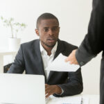 Surprised businessman getting unexpected resignation letter from a colleague