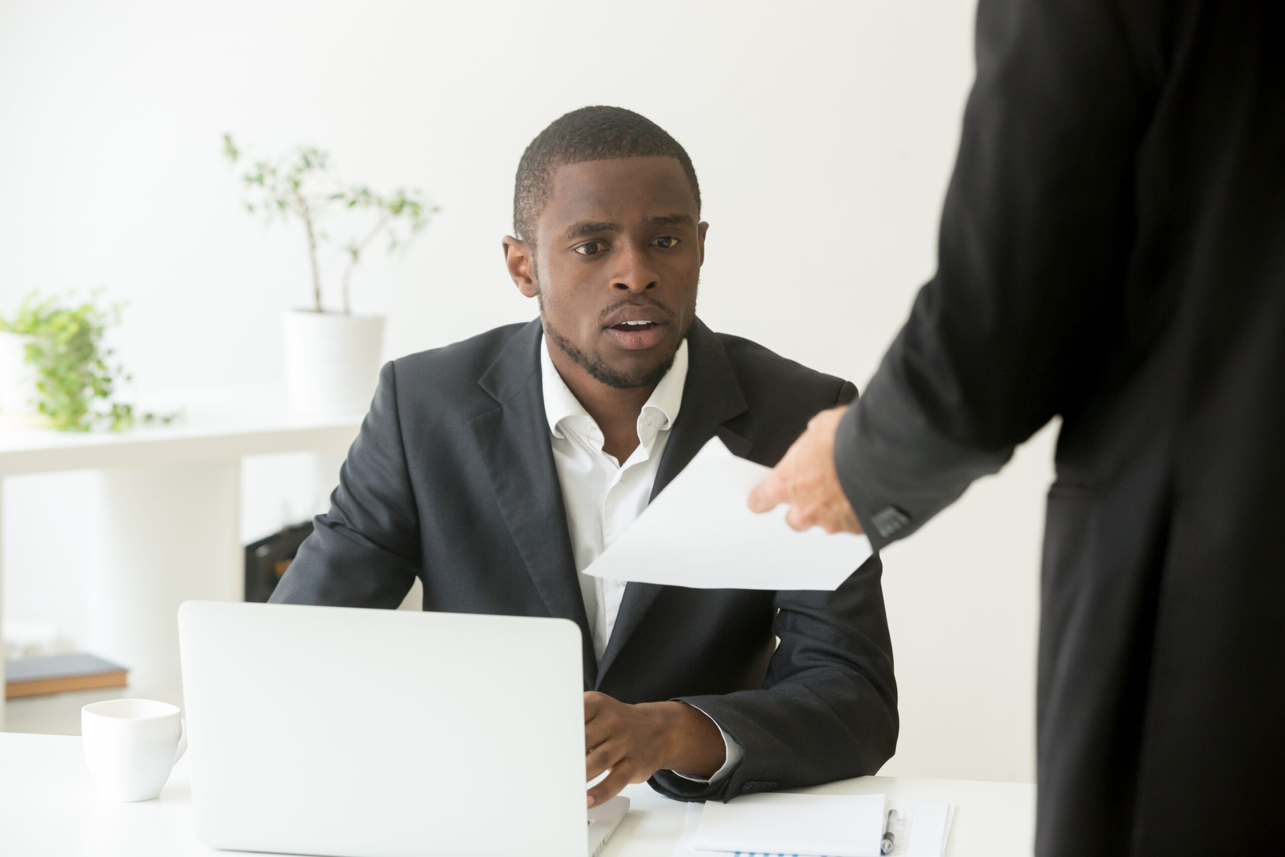 Surprised businessman getting unexpected resignation letter from a colleague